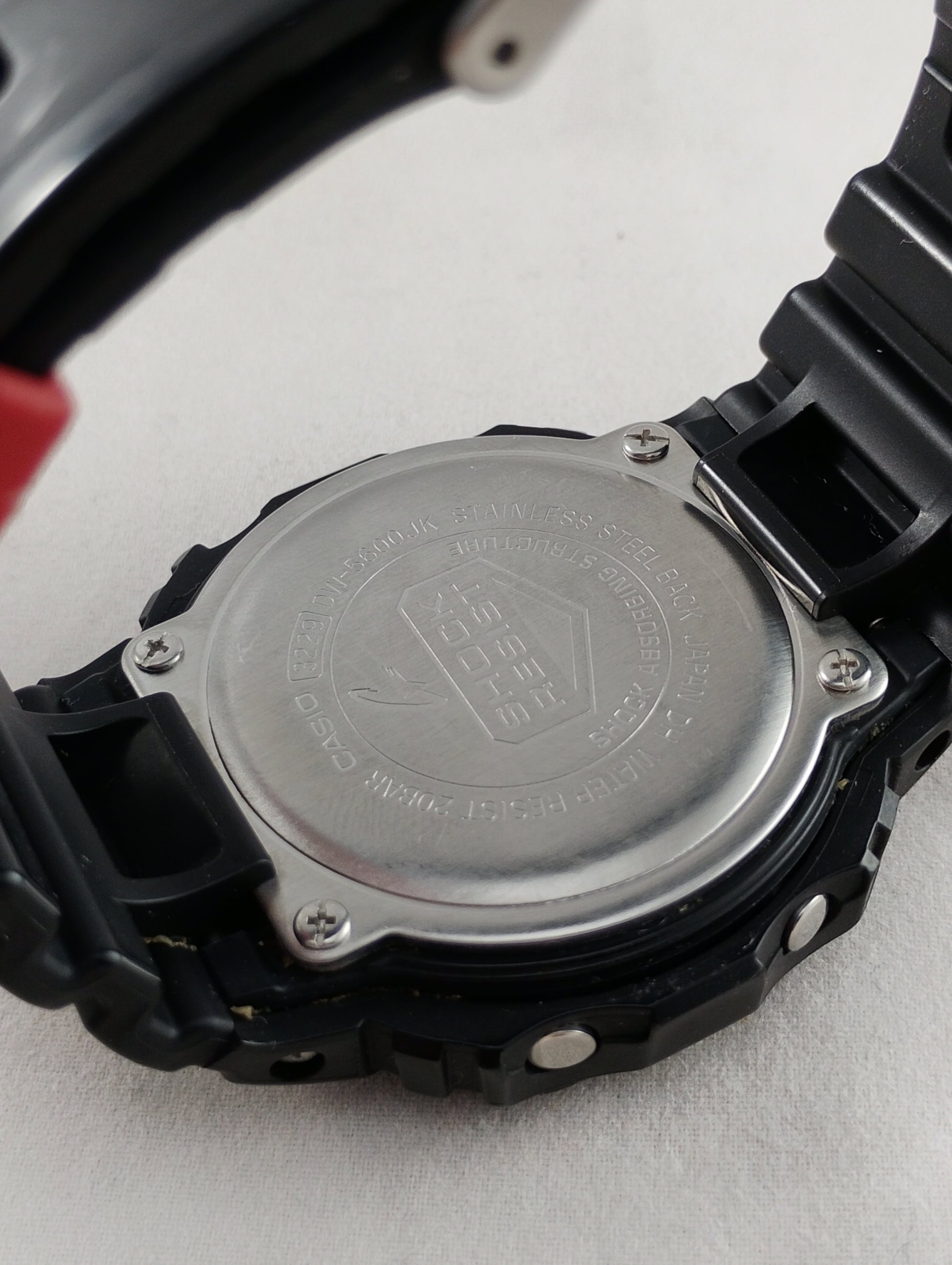 Stainless steel back case of the Casio 3229 DW-5600JK showing official engravings.