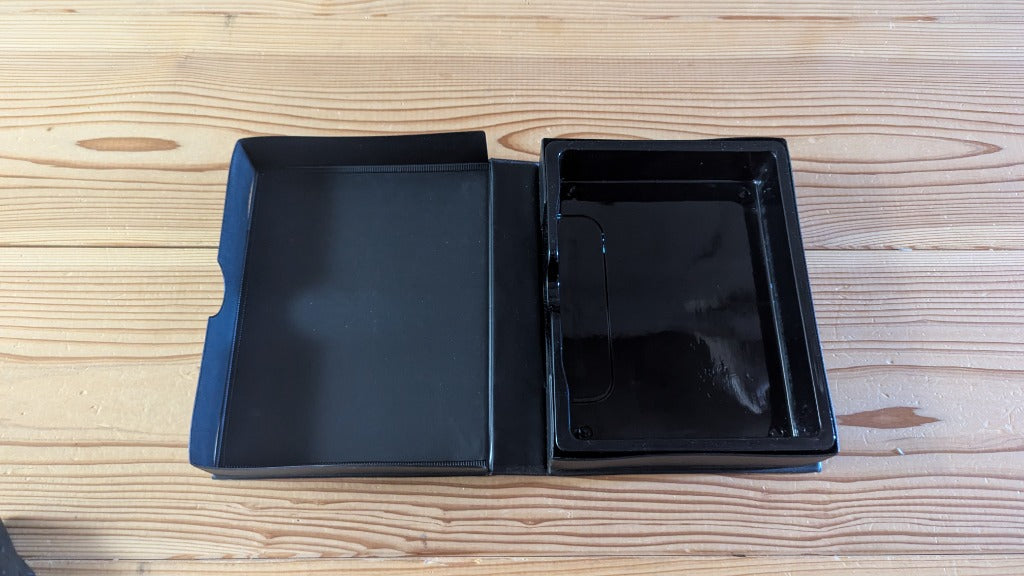 Inside view of opened SNK Neo Geo AES clamshell case showing original interior black cartridge holding tray
