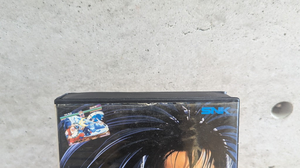 Detailed condition close-up of top edge of Shin Samurai Spirits Neo Geo AES clamshell case showing original paper insert